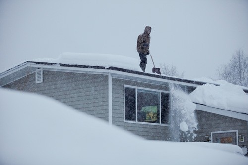 Человек очищает снег с крыши