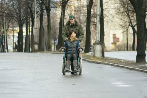 мужчина везёт инвалидное кресло с девушкой-инвалидом