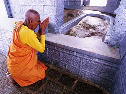 Молящийся возле углубления в камне